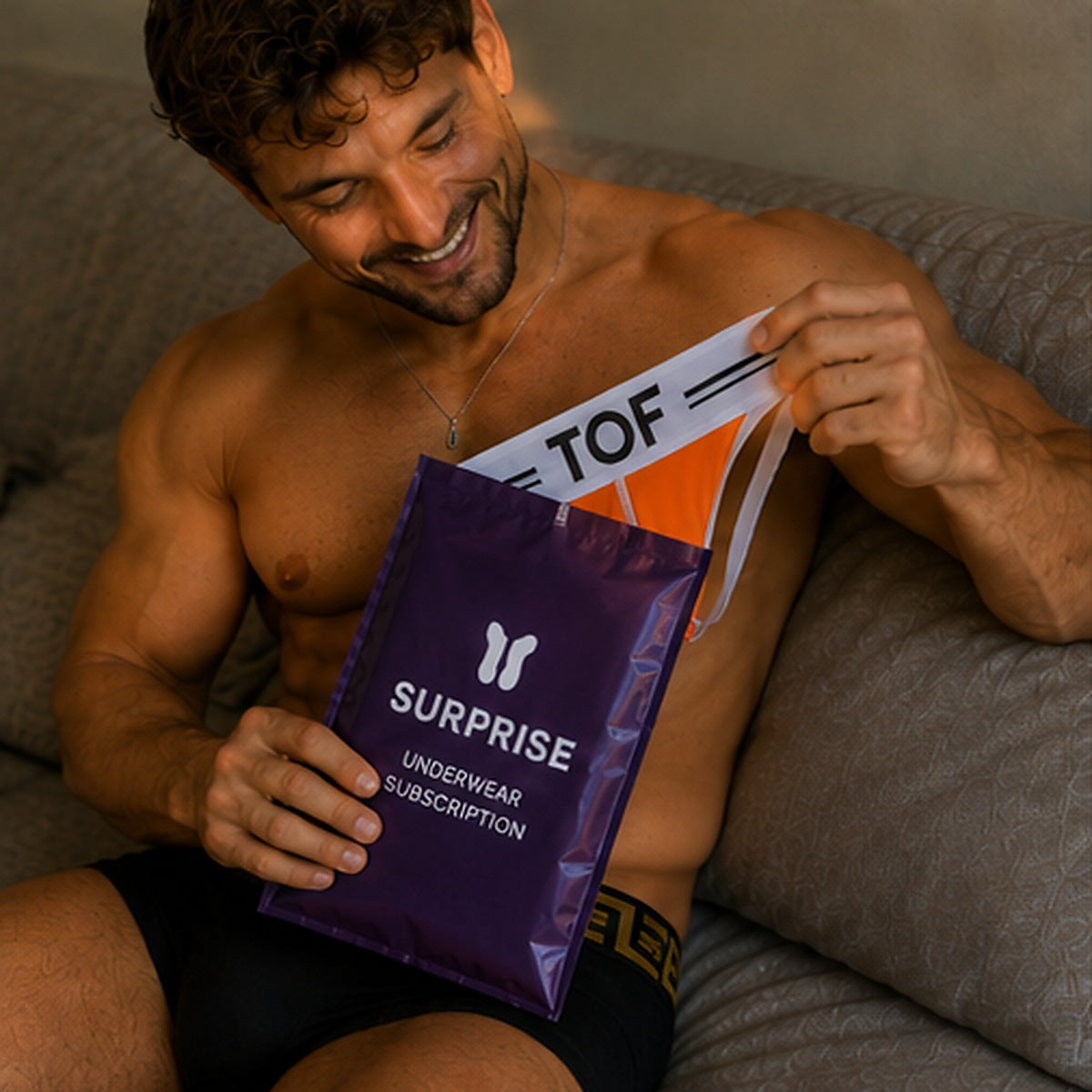 Man haalt een oranje TOF Paris jockstrap uit de paarse Surprise envelop